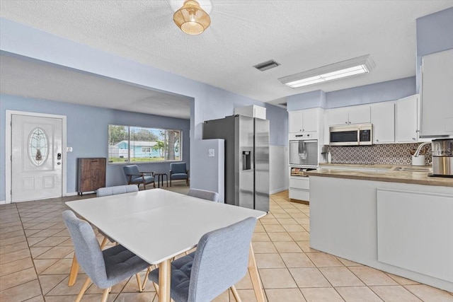 kitchen with light tile patterned floors, white cabinetry, appliances with stainless steel finishes, tasteful backsplash, and sink