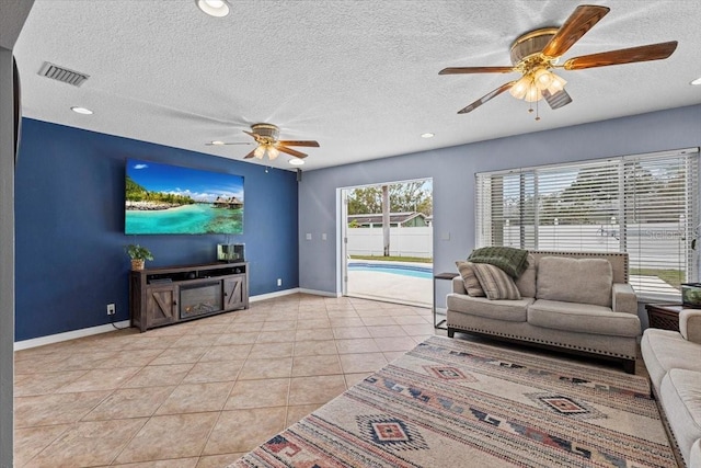 living room with a textured ceiling, ceiling fan, and light tile patterned flooring