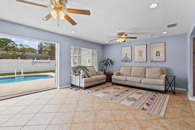 living room featuring ceiling fan, a textured ceiling, and light tile patterned floors