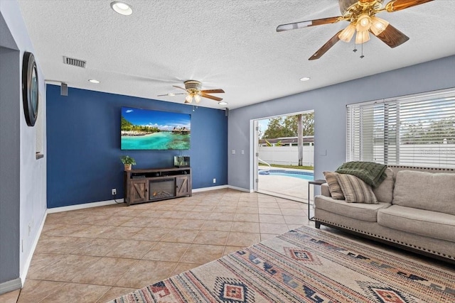 living room featuring a textured ceiling, ceiling fan, and light tile patterned floors