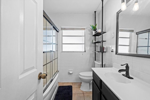 full bathroom with toilet, vanity, tile walls, tile patterned floors, and shower / bath combination with glass door