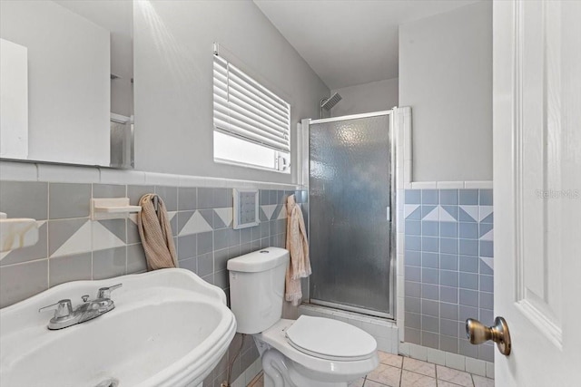 bathroom with an enclosed shower, tile walls, sink, and tile patterned flooring