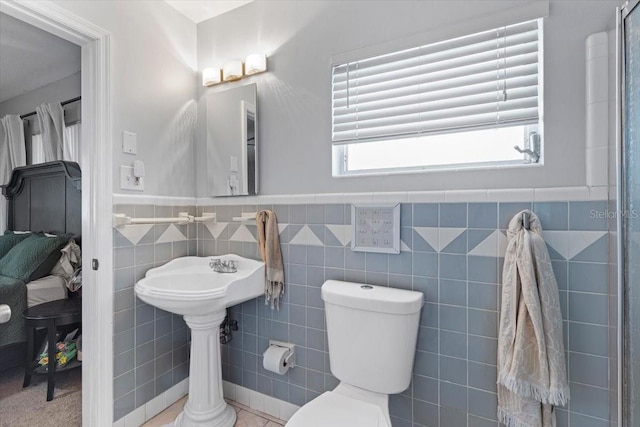 bathroom featuring tile walls and toilet