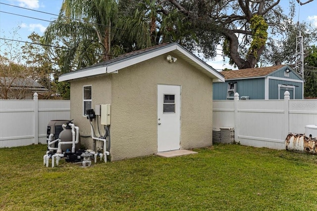 back of house featuring a lawn and a storage unit