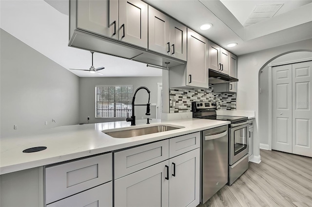 kitchen featuring gray cabinetry, ceiling fan, sink, backsplash, and appliances with stainless steel finishes