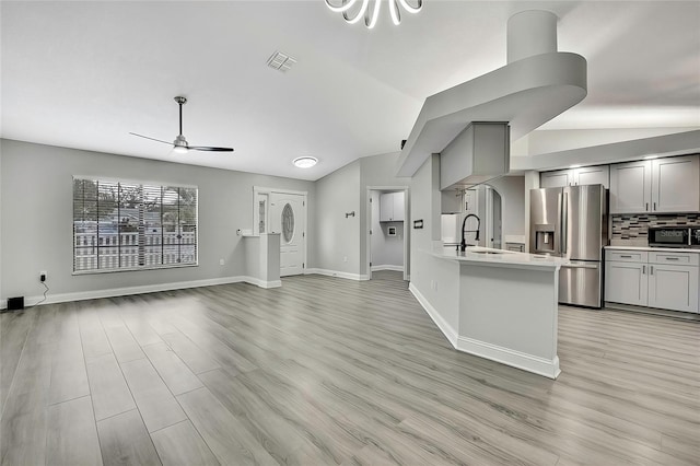 kitchen featuring decorative backsplash, stainless steel fridge, gray cabinetry, ceiling fan, and lofted ceiling