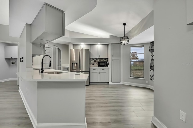 kitchen featuring sink, tasteful backsplash, stainless steel fridge with ice dispenser, decorative light fixtures, and gray cabinets