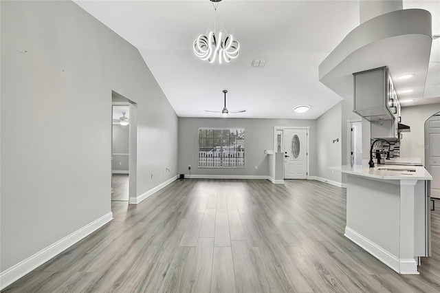 unfurnished living room with ceiling fan, light wood-type flooring, lofted ceiling, and sink