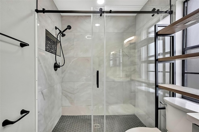 bathroom featuring a shower with shower door and toilet