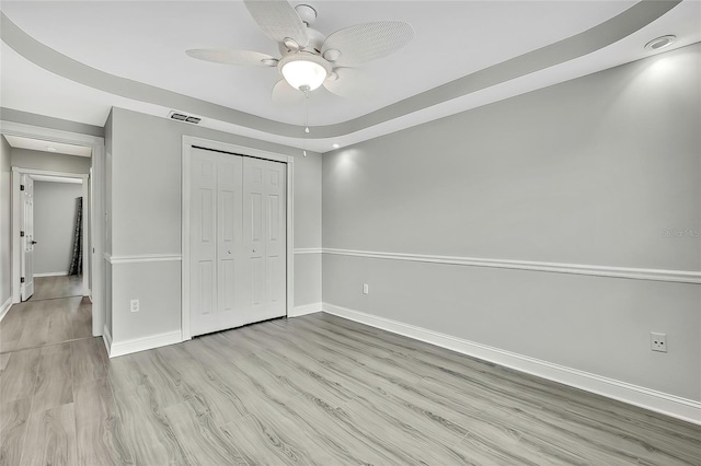 unfurnished bedroom with ceiling fan, a closet, and light hardwood / wood-style floors