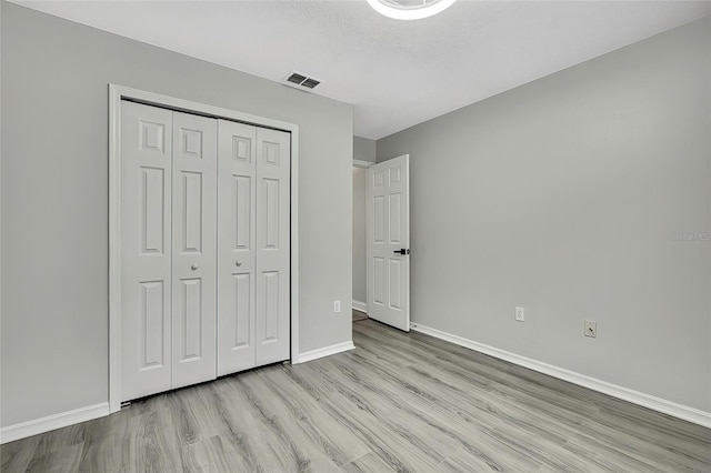 unfurnished bedroom featuring light hardwood / wood-style flooring and a closet