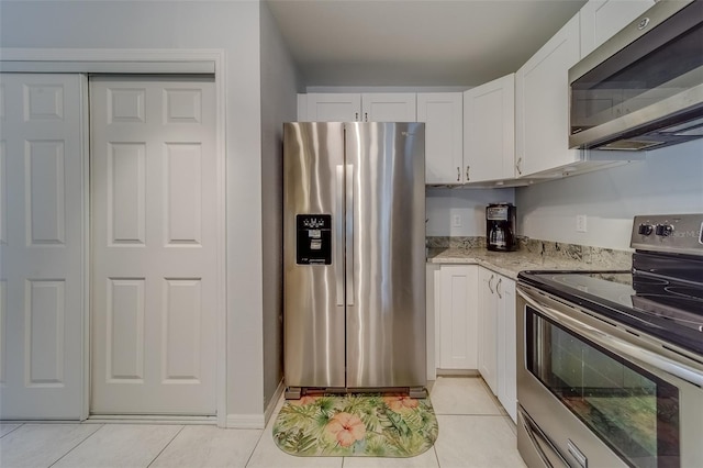 kitchen featuring white cabinets, appliances with stainless steel finishes, light tile patterned floors, and light stone counters