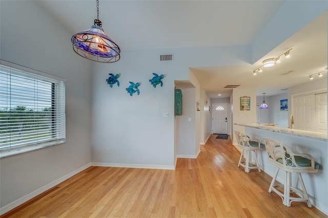 interior space with a kitchen breakfast bar, light hardwood / wood-style floors, and decorative light fixtures