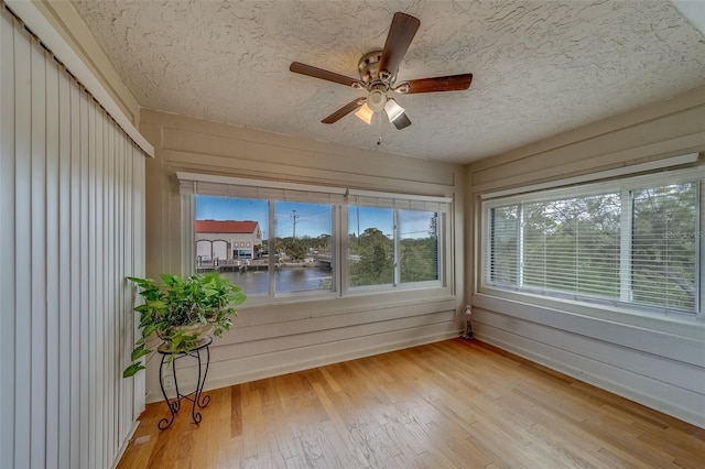 unfurnished sunroom with ceiling fan and a water view