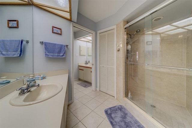 bathroom featuring a shower with shower door, vanity, and tile patterned flooring