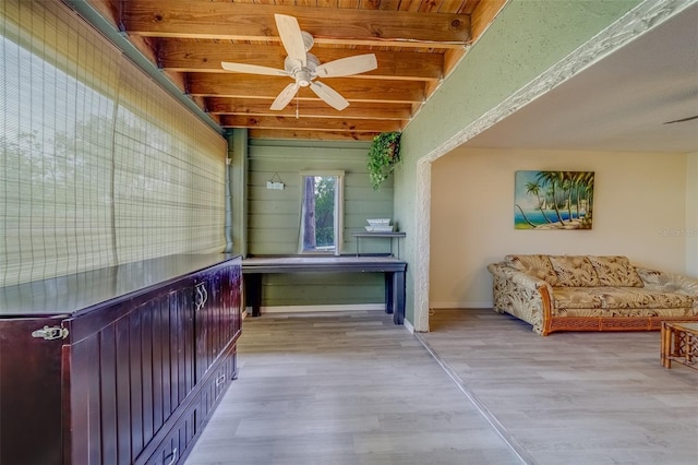 interior space with ceiling fan, wood ceiling, beamed ceiling, and light hardwood / wood-style flooring