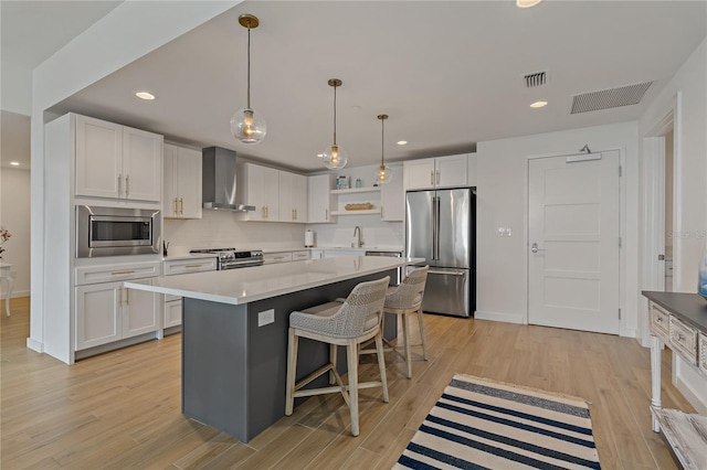 kitchen featuring stainless steel appliances, a center island, white cabinetry, and wall chimney range hood