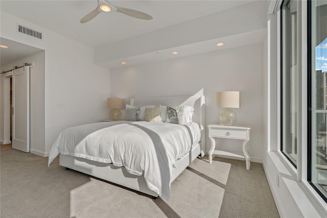 carpeted bedroom featuring ceiling fan and a barn door