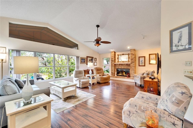 living room featuring a brick fireplace, vaulted ceiling, ceiling fan, a textured ceiling, and dark hardwood / wood-style flooring