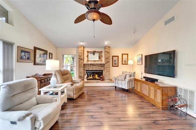 living room featuring ceiling fan, dark hardwood / wood-style flooring, lofted ceiling, and a brick fireplace