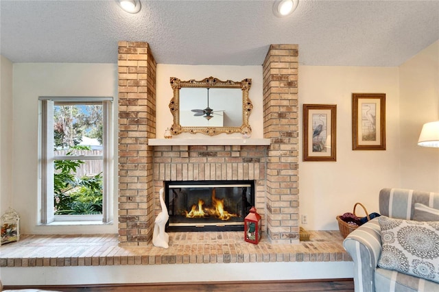 interior space featuring ceiling fan, hardwood / wood-style flooring, a textured ceiling, and a brick fireplace