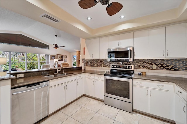 kitchen with tasteful backsplash, stainless steel appliances, vaulted ceiling, sink, and white cabinets