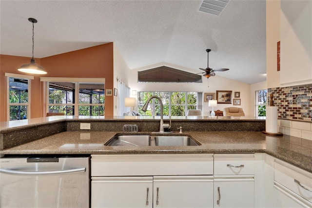 kitchen featuring white cabinets, vaulted ceiling, stainless steel dishwasher, and sink