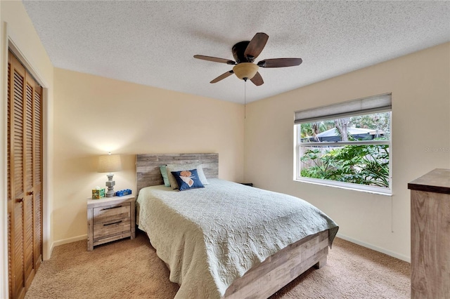 bedroom featuring a textured ceiling, ceiling fan, light carpet, and a closet