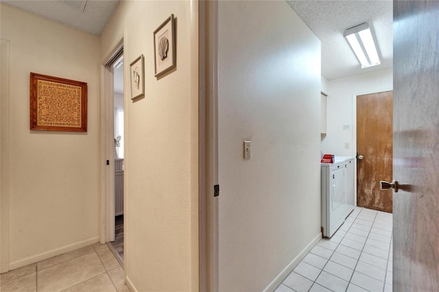 hall with a textured ceiling, washing machine and dryer, and light tile patterned floors