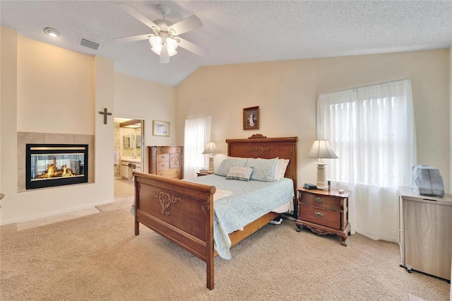 carpeted bedroom featuring multiple windows, connected bathroom, vaulted ceiling, and ceiling fan