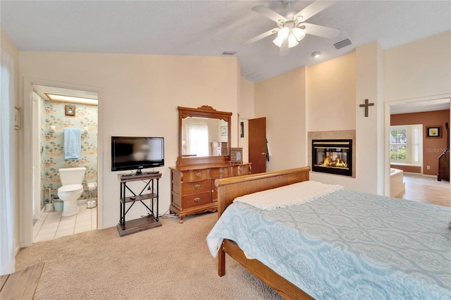 bedroom featuring ensuite bathroom, a multi sided fireplace, vaulted ceiling, ceiling fan, and light colored carpet