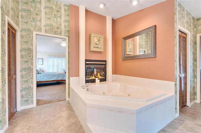 bathroom with tiled bath, ceiling fan, tile patterned flooring, and a textured ceiling