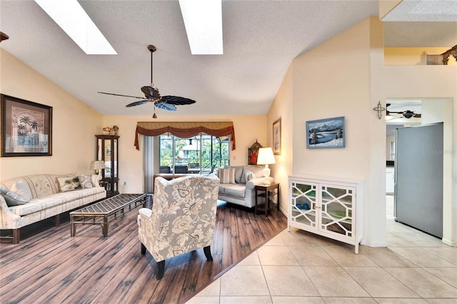 tiled living room featuring vaulted ceiling with skylight and ceiling fan