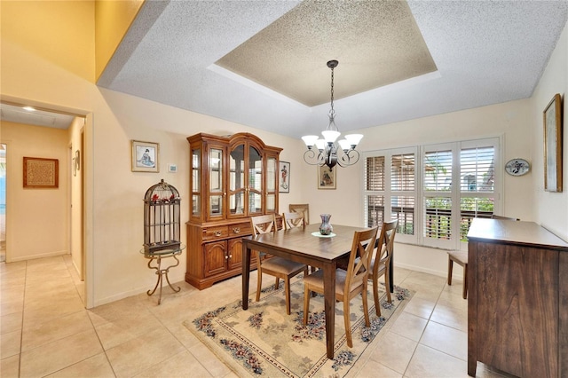 dining area featuring a textured ceiling, a raised ceiling, a notable chandelier, and light tile patterned flooring