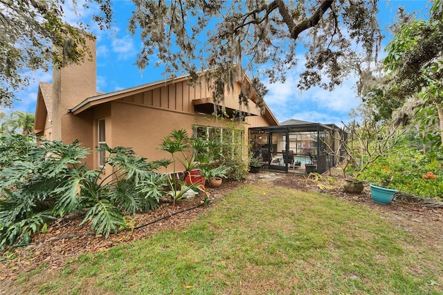 rear view of property with a lawn and glass enclosure