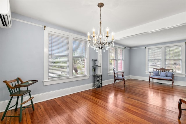 living area featuring hardwood / wood-style floors, a chandelier, and a wall mounted air conditioner