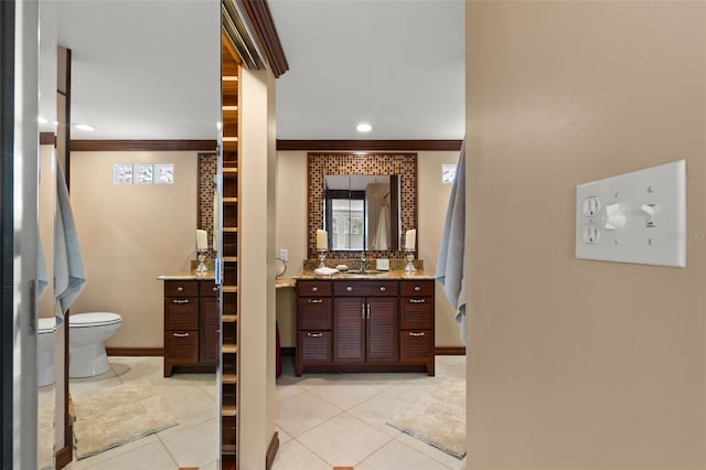 bathroom with toilet, vanity, tile patterned floors, and crown molding