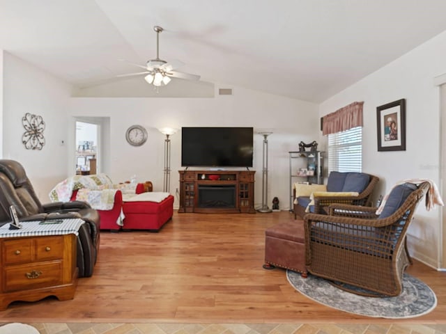 living room featuring ceiling fan, light wood-type flooring, and vaulted ceiling