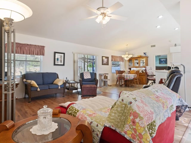 living room featuring ceiling fan with notable chandelier, hardwood / wood-style flooring, and vaulted ceiling