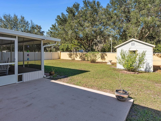 view of yard featuring a patio, a sunroom, and a storage shed