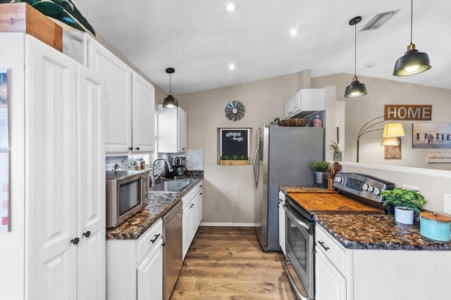 kitchen with appliances with stainless steel finishes, decorative backsplash, white cabinets, decorative light fixtures, and sink