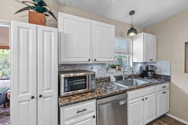 kitchen with white cabinets, stainless steel appliances, sink, decorative light fixtures, and backsplash