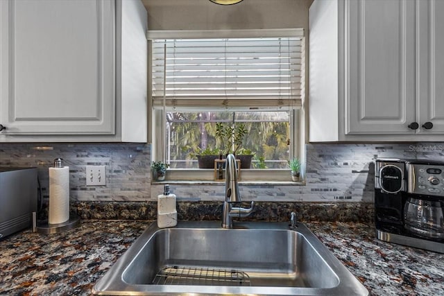 kitchen featuring sink, white cabinets, tasteful backsplash, and dark stone counters