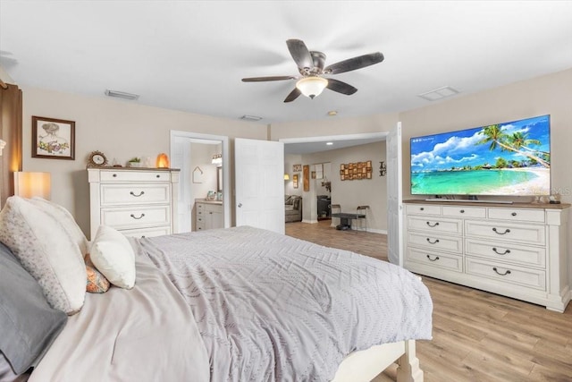 bedroom with ensuite bath, ceiling fan, and light hardwood / wood-style floors