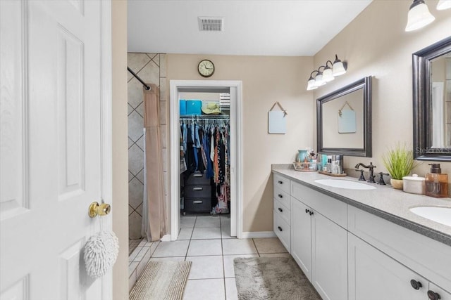 bathroom featuring a tile shower, tile patterned floors, and vanity