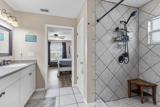 bathroom with ceiling fan, tiled shower, tile patterned flooring, and vanity