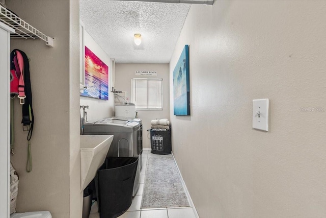 laundry area featuring washer and dryer, light tile patterned flooring, and a textured ceiling