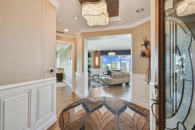 entrance foyer with hardwood / wood-style flooring, ornate columns, ornamental molding, and a chandelier