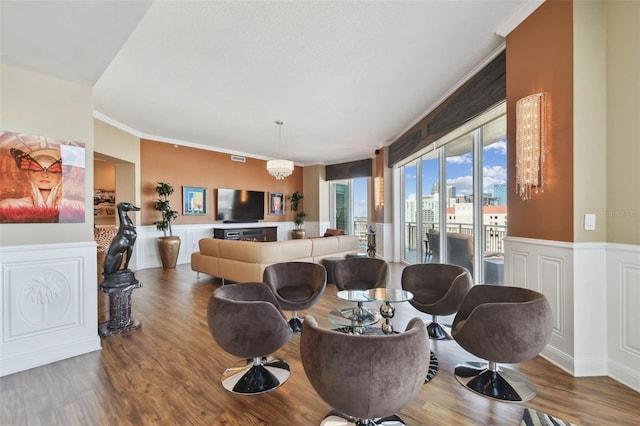 living room featuring hardwood / wood-style floors, crown molding, and a notable chandelier