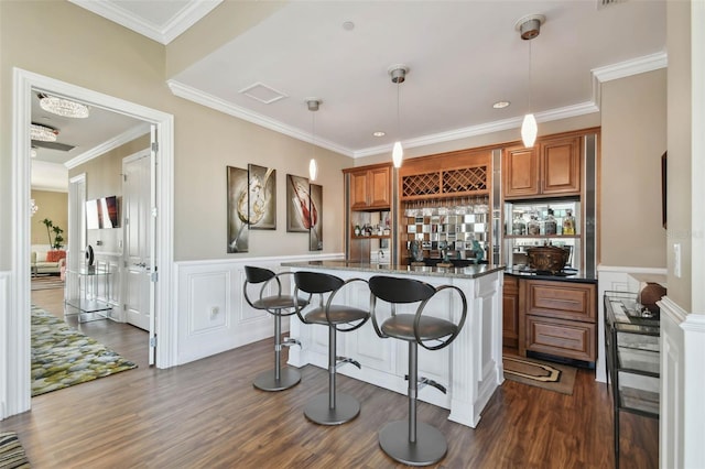 bar featuring pendant lighting, ornamental molding, dark wood-type flooring, and dark stone countertops